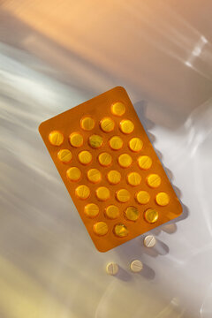 Orange blister pack of round yellow pills with some loose tablets
