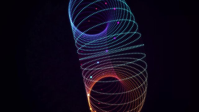 Glowing 3D torus made of neon dotted lines rotating on a black background, vibrant rainbow gradient light particles moving in a seamless loop
