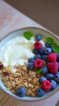 Delicious bowl of greek yogurt topped with granola and fresh berries for healthy breakfast. Granola bowl with blueberries and raspberries close up.