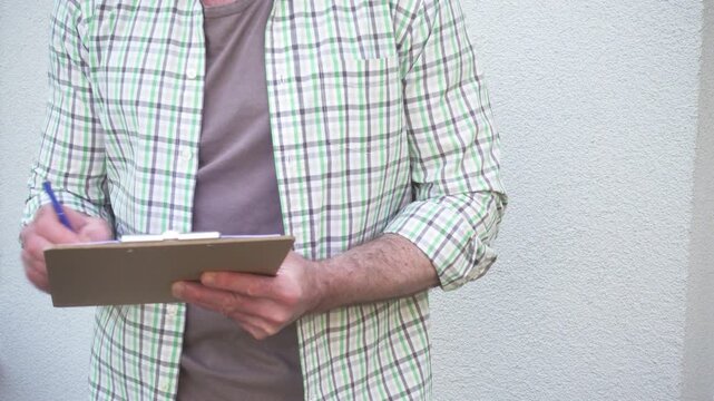 Man conducts a social survey outside home, writing on clipboard. Community research, opinion polling and data collection. Symbolizes public engagement and research. Ideal for social science content