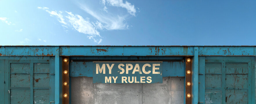 Metal container structure featuring illuminated typography sign reading My Space My Rules against concrete wall and sky background. Concept for independence, boundaries, freedom, and property control.