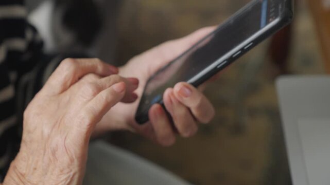 Senior woman comfortably uses a smartphone for everyday online tasks at home, representing older generation adaptability and digital technology skills.