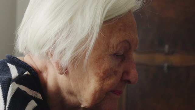 Close-up pan from an elderly woman's face to her hands typing on a laptop keyboard, highlighting digital skills and technology adoption.