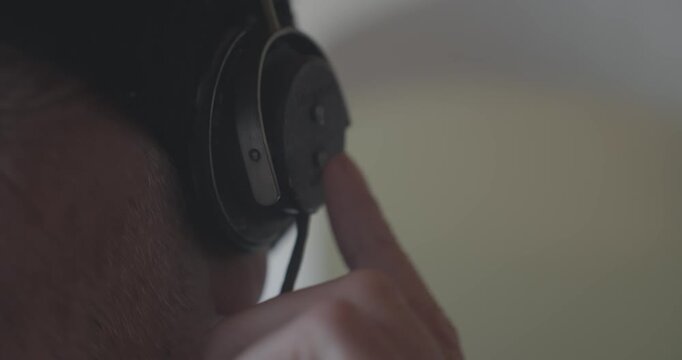 Close-up of a radio operator listening through vintage headset earphones, creating an atmospheric scene evoking surveillance, espionage and military communications.