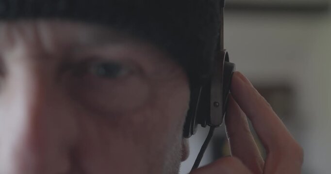 Close-up of a radio intelligence operator listening through vintage headset earphones, evoking surveillance, espionage, military communications and police drama.
