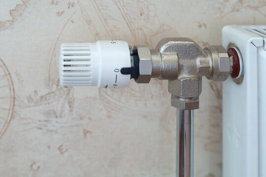 Thermostatic radiator valve with numbered control dial is attached to a metal heating pipe. Concept of heating regulation, temperature control, energy efficiency and household comfort.