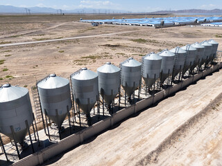 rows of metal grain silos in desert landscape © zhu difeng