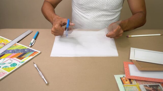Creative man using scissors to cut transparent acetate sheet for handmade craft project