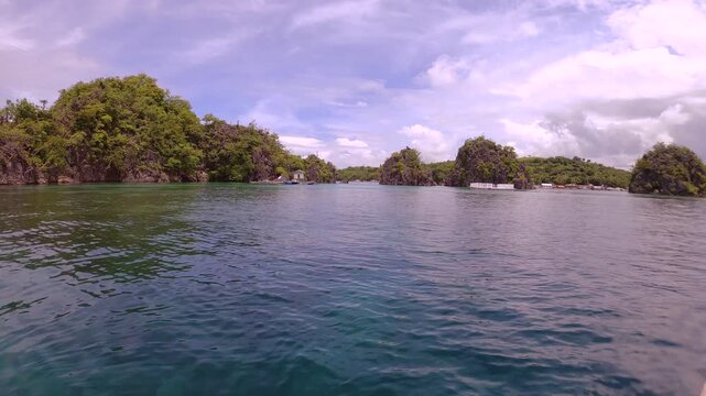 Fast spinning view left to right look out to shallow blue green turquoise peaceful lagoon from a small boat to coral rocks at Siete Pecados Marine Park Coron Philippines during sunny blue sky good day