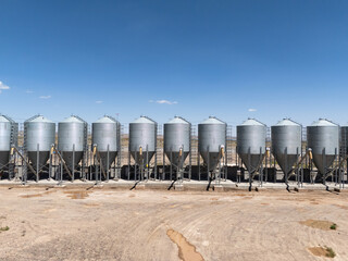 row of silver metal grain silos under blue sky © zhu difeng