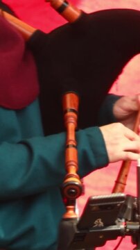 A person in medieval attire plays the bagpipes on a scenic background