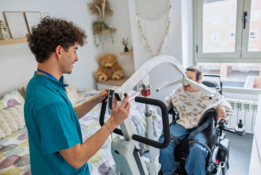 Caregiver assisting patient with mobility hoist at home