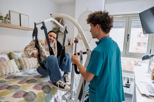 Caregiver helping woman use patient lift happily