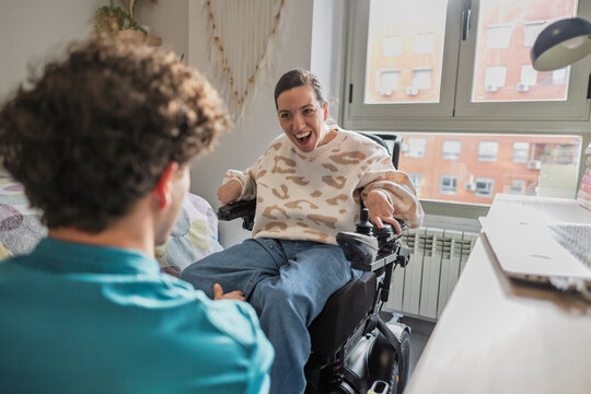 Woman with disability sitting on electric wheelchair talking with friend
