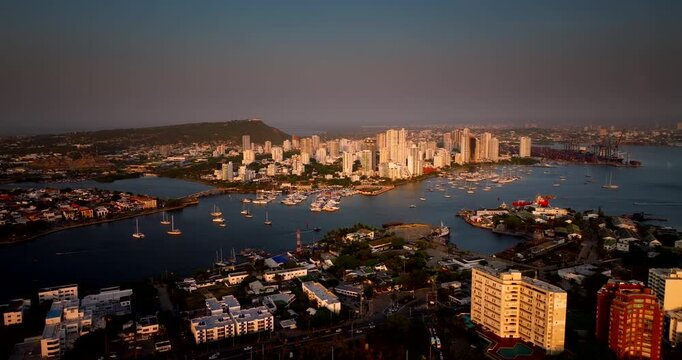 Sailboats moored n Cartagena bay with Bocagrande skyline at golden sunset in Cartagena, Colombia. Aerial drone, cityscape