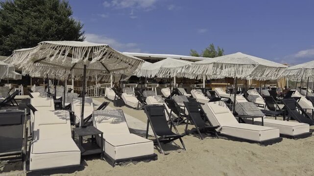 Rows of empty sun loungers and fringed umbrellas set up on the sand at a beach club in Chalkidiki Greece before opening
