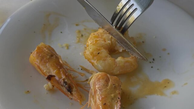 Grilled shrimp pieces and sauce remain on a white plate after a seafood meal in Chalkidiki Greece