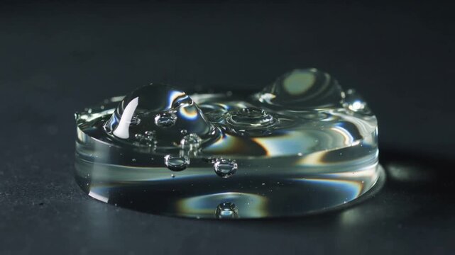 Impacting droplet creating central dome on transparent gel disc at studio tabletop, forming bubbles