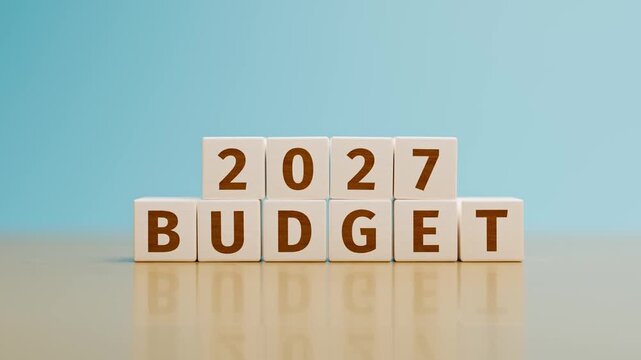 Wooden toy cubes forming the text "2027 BUDGET". Concept for planning the yearly budget for 2027. Camera moving from high angle view to same level. Crane movement