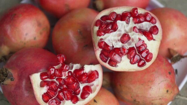 Close-up of fresh whole and sliced pomegranates showing juicy red arils
