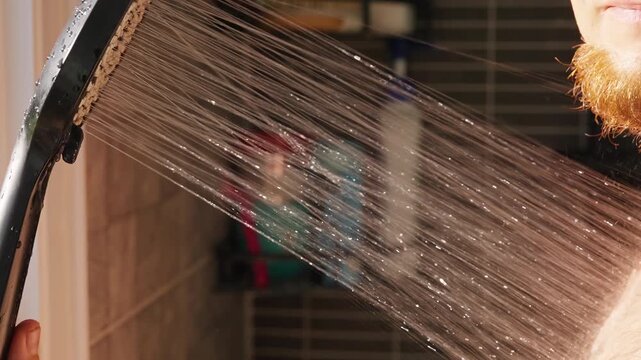 Bearded Person Rinses Bare Shoulder With a Shower in Tiled Bathroom, Water Spray Supports Daily Hygiene and Personal Care