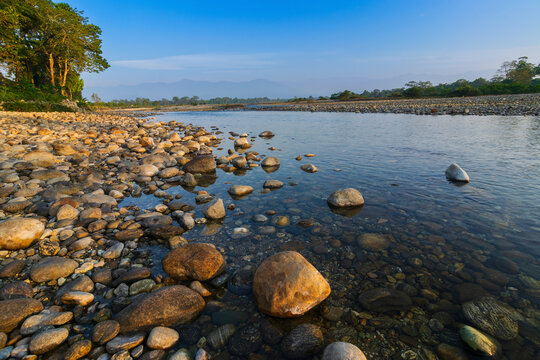 Murti river in the morning, riverbed in foreground with flowing water and stones. Scenic beauty of Dooars landscape, West Bengal, India. Dooars is popular tourist destination for natural landscapes.