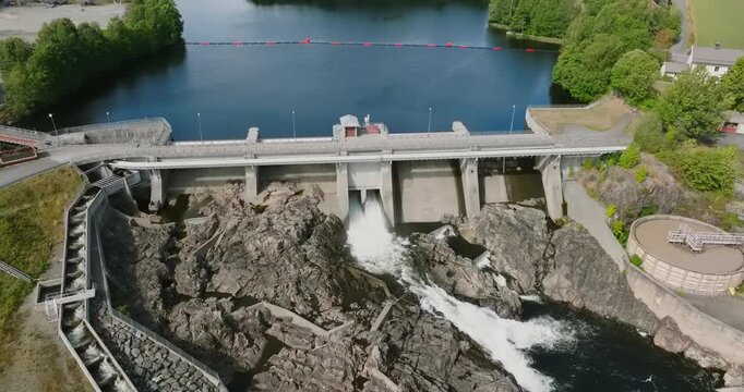 Aerial view of Rykene dam and hydroelectric power station in slow motion showing forested surroundings