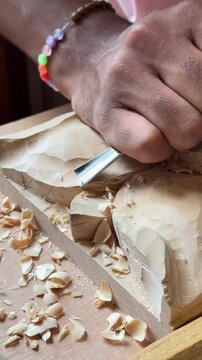 Extreme close up of woodcarver hands precisely shaping timber with sharp steel gouge chisel