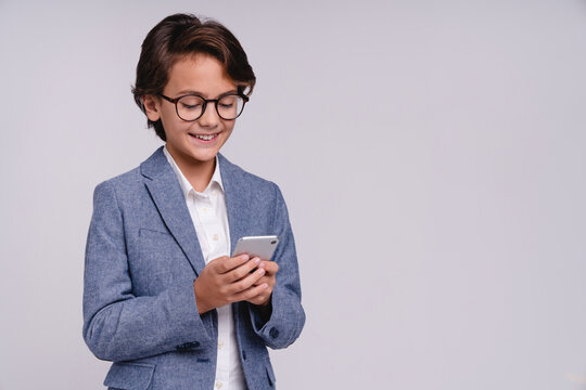 Smiling clever young boy using mobile phone isolated on grey background, childhood, technology, communication, digital lifestyle, education and smart kid concept