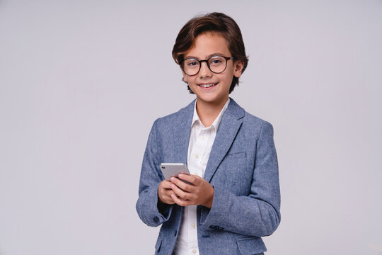 Cheerful little boy in formal attire using mobile phone isolated on grey background, childhood, technology, communication, future businessman, digital lifestyle and career concept