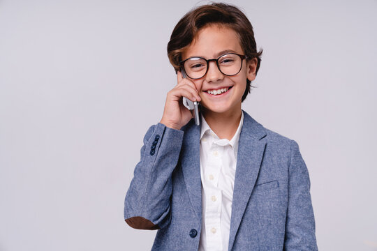 Cheerful smiling little boy talking on phone in formal clothes isolated on grey background, childhood, communication, technology, future businessman and lifestyle concept
