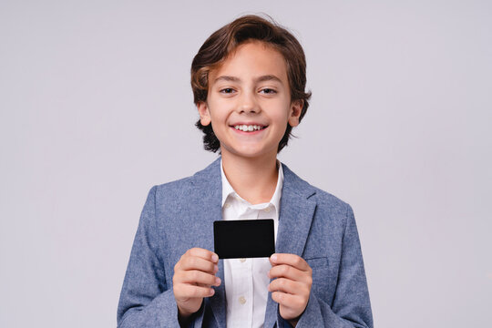 Handsome little boy in formal attire presenting credit card isolated on grey background, childhood, finance, payment, shopping, future businessman, money and lifestyle concept