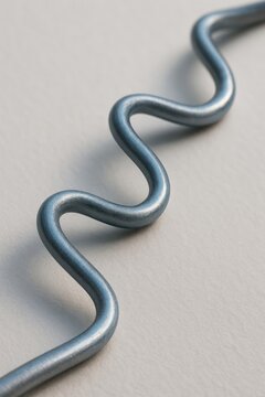 Macro close-up of a flexible corrugated titanium wire bent into smooth repeating sinusoidal waves
