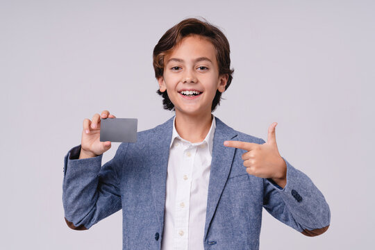 Smiling little kid pointing at credit card isolated on grey background, childhood, finance, payment, shopping, money, future businessman and lifestyle concept