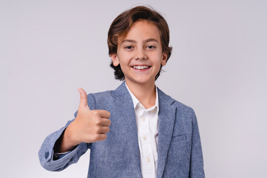Smiling cheerful kid showing thumb up isolated on grey background, childhood, positive emotion, approval, happiness, success, confidence and cheerful lifestyle concept