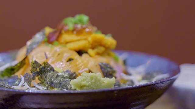 Close-up of a premium donburi bowl topped with assorted sashimi, creamy uni, and vibrant salmon roe over steamed sushi rice, beautifully arranged for an elegant Japanese meal.