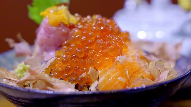 Close-up of a premium donburi bowl topped with assorted sashimi, creamy uni, and vibrant salmon roe over steamed sushi rice, beautifully arranged for an elegant Japanese meal.