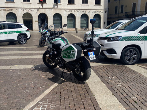 Polizia Locale vehicles including a Yamaha Tracer 7 motorcycle and cars on cobblestone pavement in Cremona, Italy