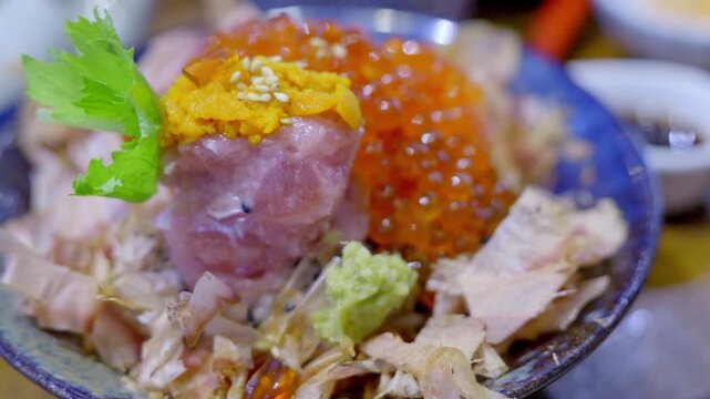 Close-up of a premium donburi bowl topped with assorted sashimi, creamy uni, and vibrant salmon roe over steamed sushi rice, beautifully arranged for an elegant Japanese meal.