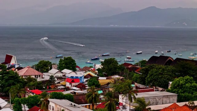 Aerial view of Gili Trawangan with boats anchored in the turquoise bay and coastal village buildings in Pemenang, West Nusa Tenggara, Indonesia.