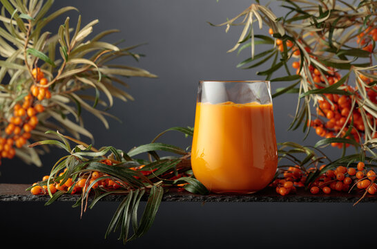 Glass of sea buckthorn juice with fresh berries on a branches.
