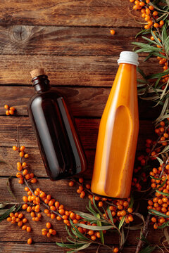 A dark glass pharmacy bottle filled with sea buckthorn oil and a bottle of sea buckthorn juice.