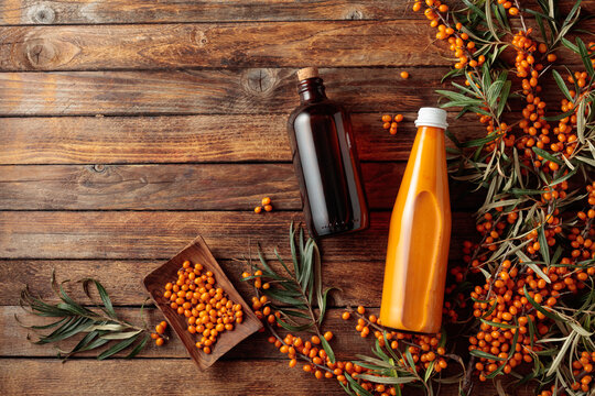 A dark glass pharmacy bottle filled with sea buckthorn oil and a bottle of sea buckthorn juice.