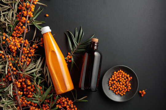 A dark glass pharmacy bottle filled with sea buckthorn oil and a bottle of sea buckthorn juice.