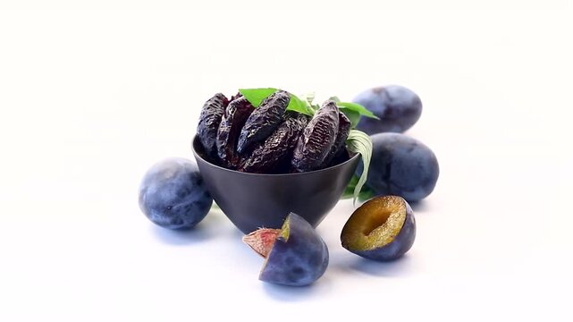 Natural prune pieces with ripe plums isolated on white background