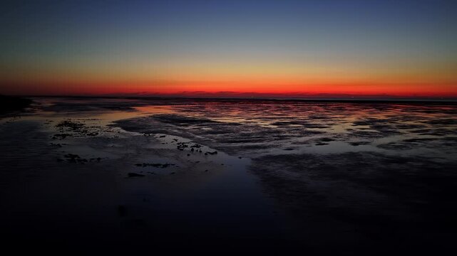 Low aerial perspective flying over the Wadden Sea mudflats at twilight in the Netherlands