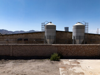 industrial grain silos and brick wall under clear blue sky © zhu difeng