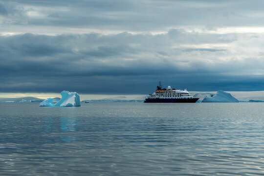 Antarctica, Antarctic Peninsula, in the Lemaire Channel. A cruise ship is anchoring in the calm sea.
