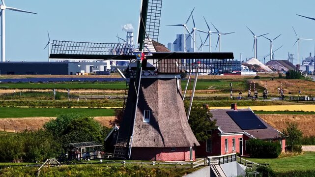 Traditional De Goliath windmill stands before modern wind turbines near Eemshaven, Groningen, contrasting historic Dutch heritage with renewable energy development