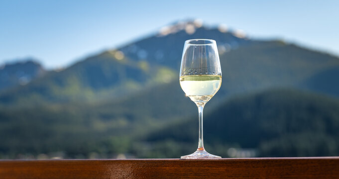 Glass of White Wine on Cruise Ship Railing with Scenic Alaska Mountain Background
